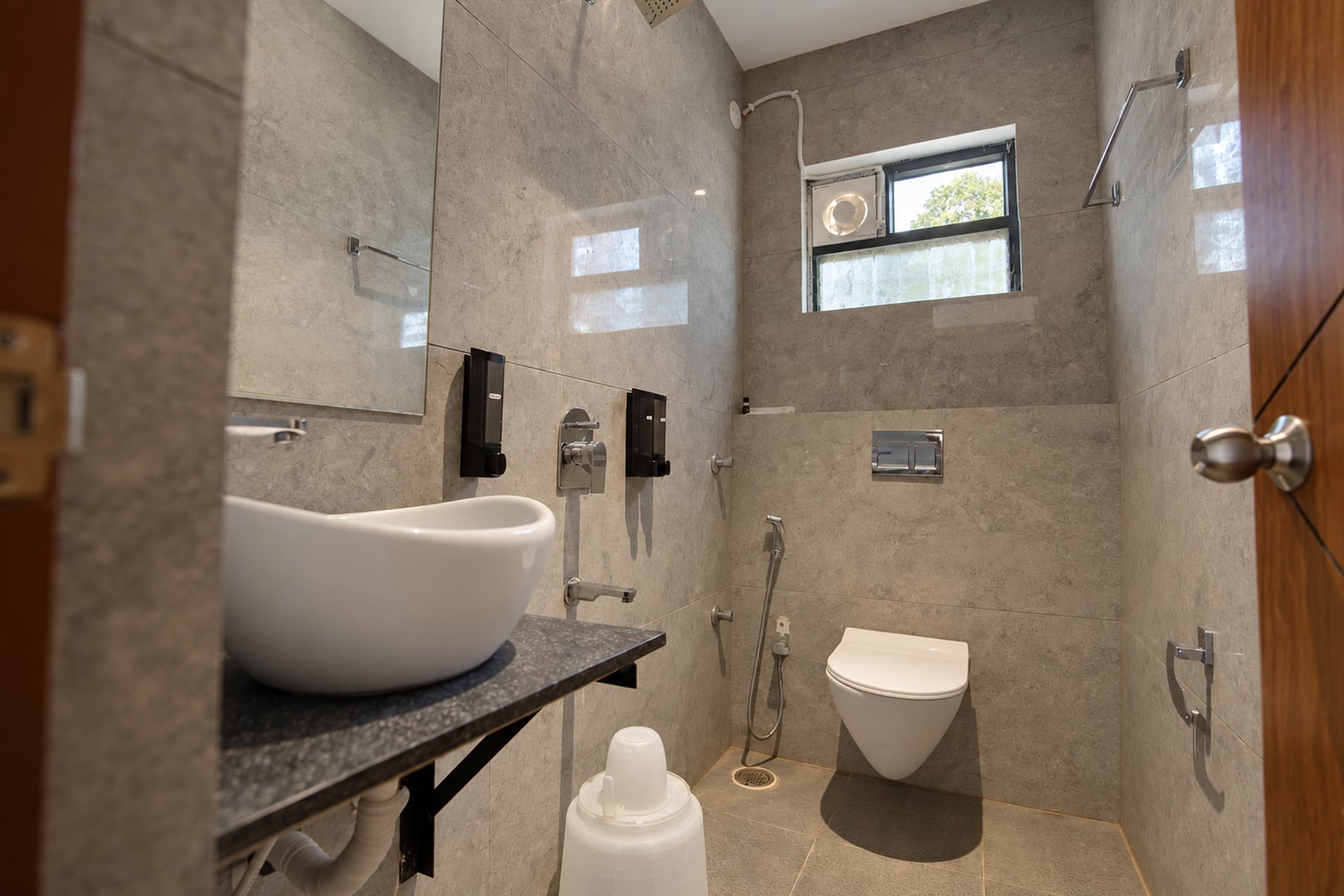 Private stone-tiled bathroom with a vessel basin, mirror and rainfall shower