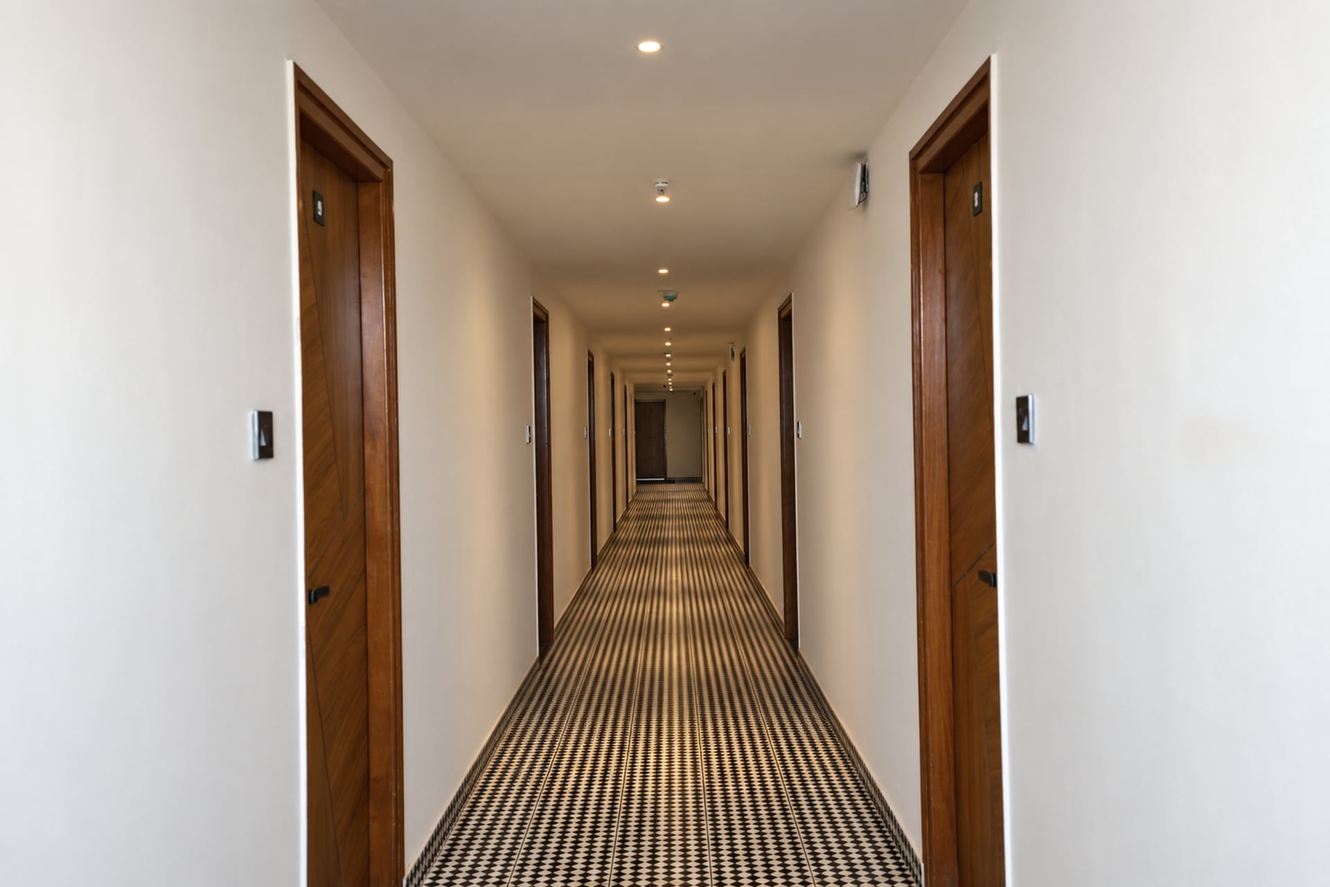 Old Mill guest corridor with timber doors and a geometric tiled floor