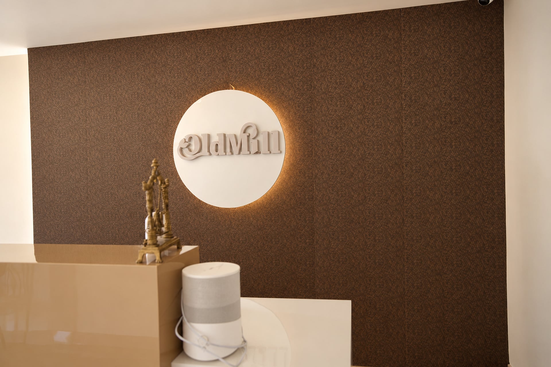 Illuminated Old Mill emblem on the textured reception wall