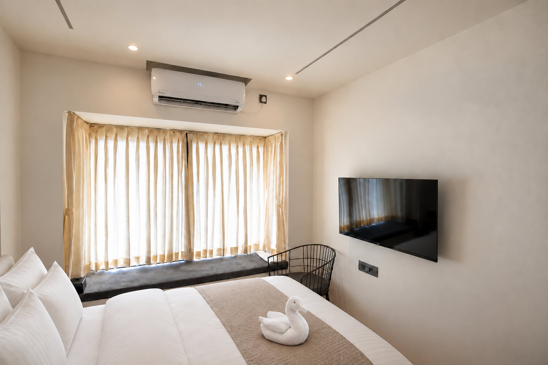 Guest room with a television, window seat and soft daylight through the curtains