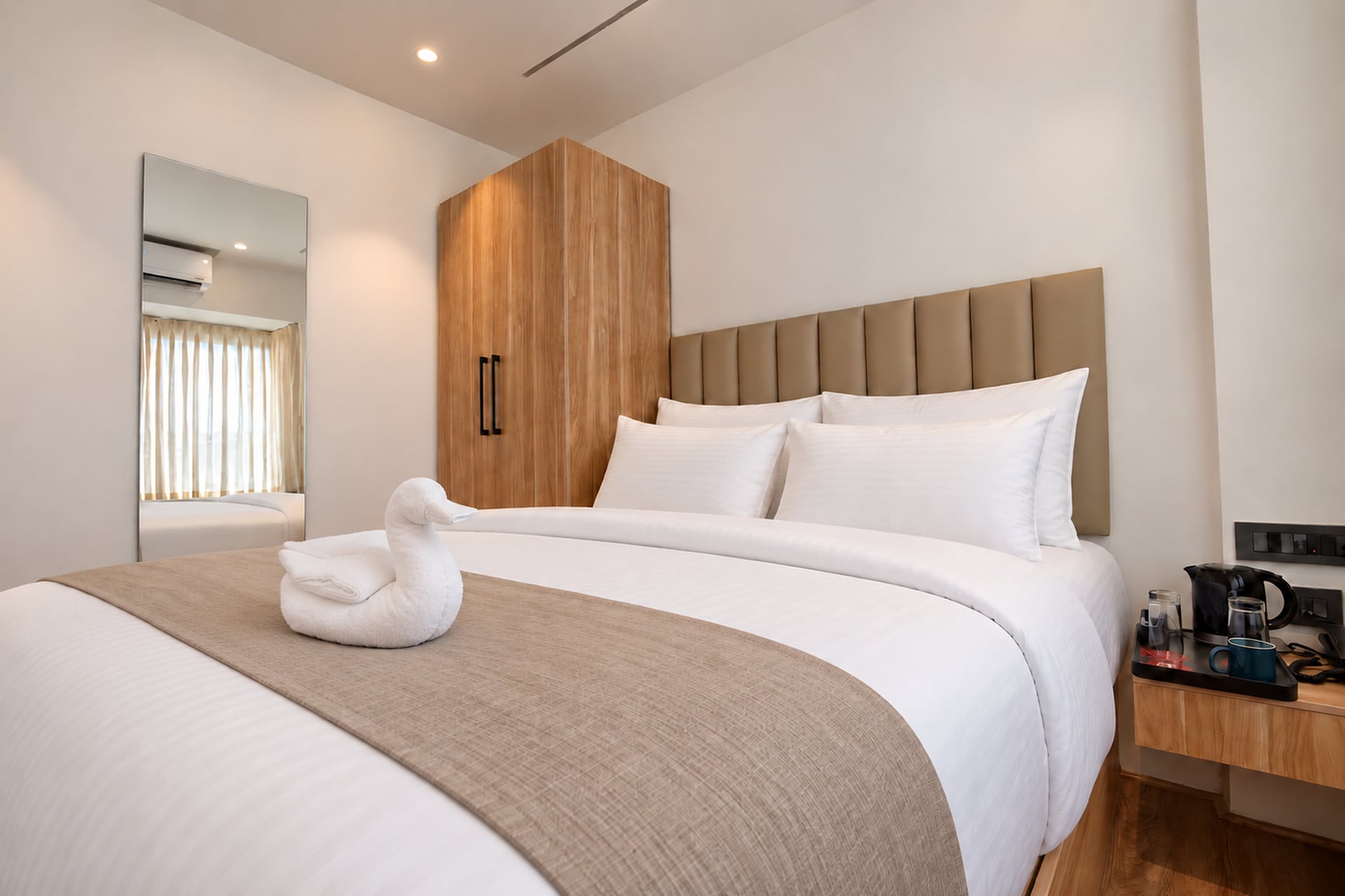 Old Mill guest bed with layered white pillows, a warm woven runner and bedside refreshments