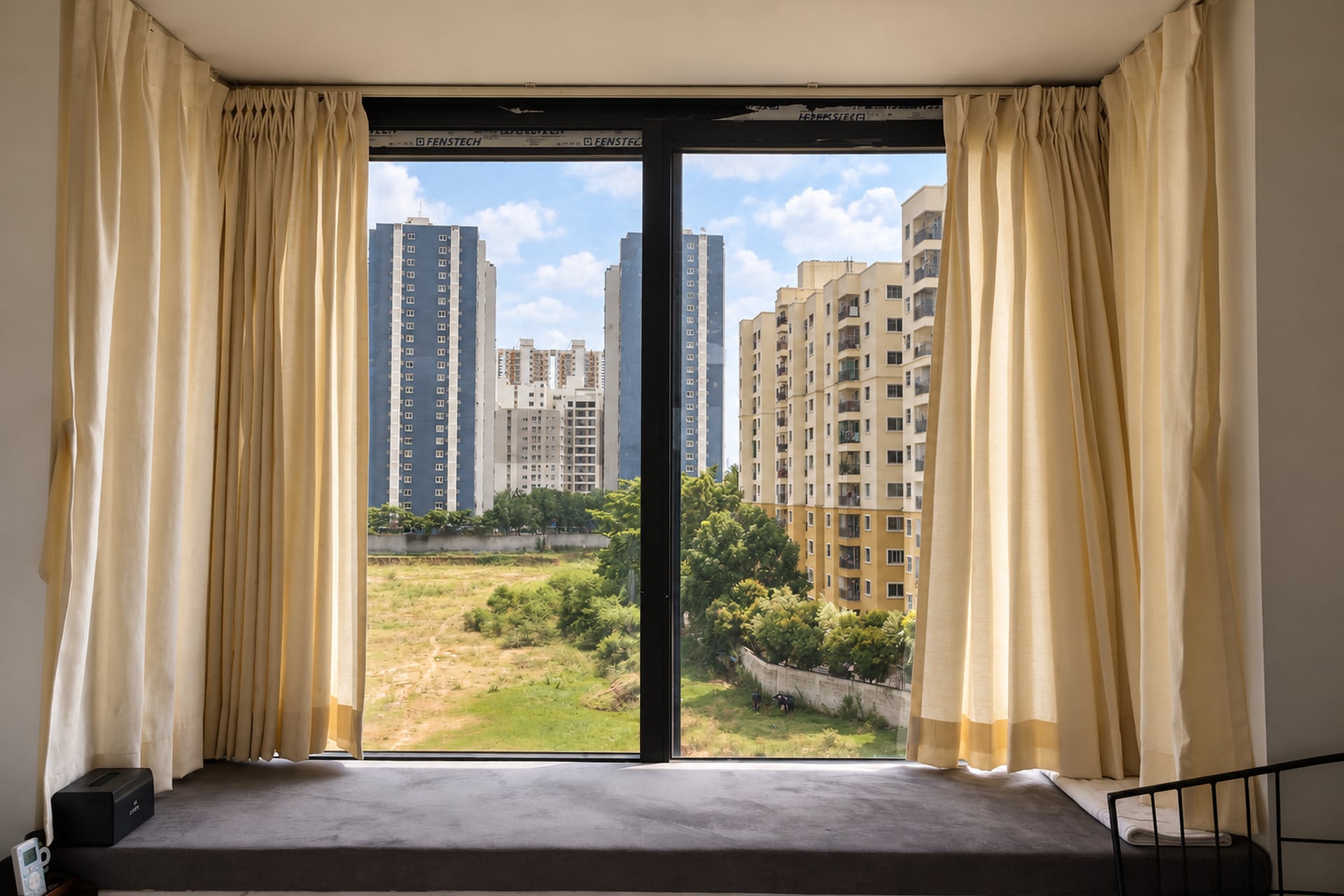 Guest-room window seat overlooking the greenery and buildings of East Bengaluru